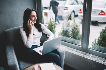 Pensive woman talking on smartphone in armchair