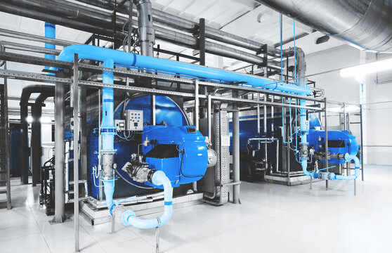 Interior of modern industrial gas boiler room with two gas boilers and pipes for supplying gas and steam. Blue toning