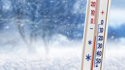 Thermometer on a background of winter forest shows 20 degrees below zero - obrazy, fototapety, plakaty