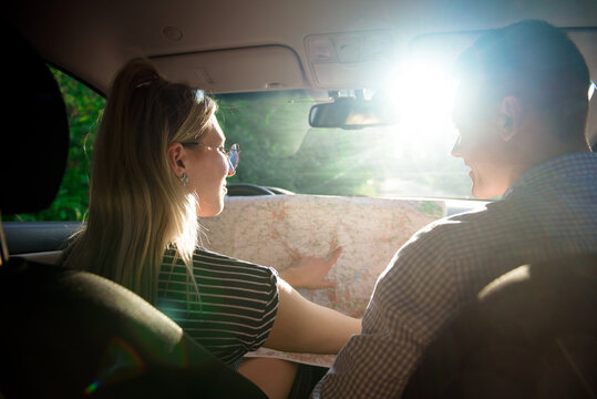 Happy couple with map in car. Smiling man and woman using a map on the road.