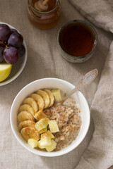 Buckwheat porridge with fruit, green tea, fruit and honey on a linen tablecloth. Rustic style.