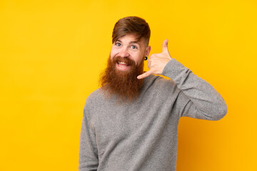 Redhead man with long beard over isolated yellow background making phone gesture. Call me back sign
