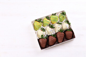 Box of assorted chocolate covered strawberries as a romantic gesture. Berries glazed in dark, white and pistachio flavored chocolate. Close up, copy space, top view, isolated background.