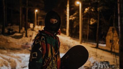 Man in a colorful jacket holding a snowboard