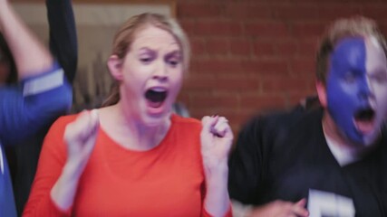 CU of a man and woman overcome with excitement hugging each other, man gets face paint on woman's face.