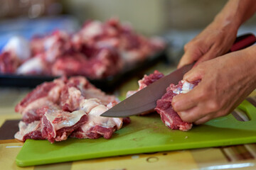Woman's hand slicing beef on a wooden board