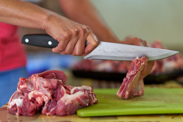Woman's hand slicing beef on a wooden board