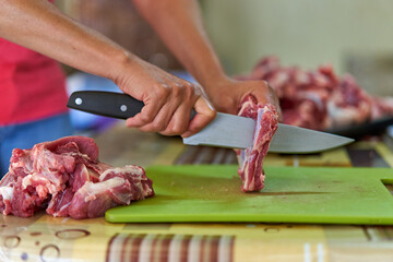 Woman's hand slicing beef on a wooden board