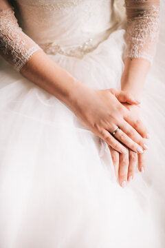 Morning of the bride before the wedding ceremony. Color photo of hands on a wedding dress.