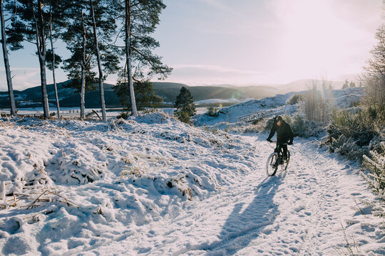 A man pedalling hard up a snowy hill in the countryside