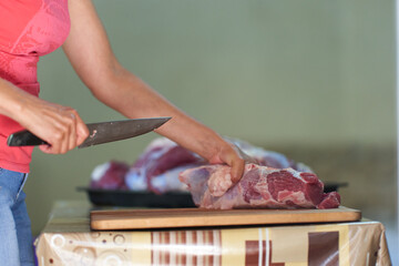Woman's hand slicing beef on a wooden board