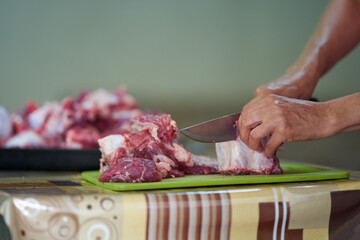 Woman's hand slicing beef on a wooden board