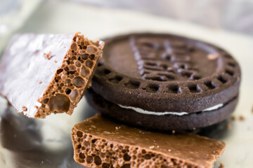 Two pieces of milk aerated chocolate with a round chocolate chip cookie close up