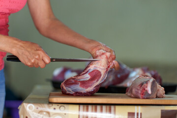 Woman's hand slicing beef on a wooden board