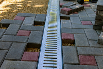 A gloved craftsman lays paving stones in layers. Brick paving slabs for professional use. Laying gray concrete paving slabs in the courtyard of the house on a sandy foundation.