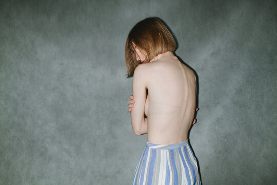 Young pretty topless woman posing on gray background