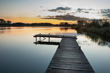 Wooden pier on a calm lake, view after sunset