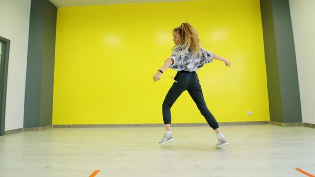 Woman dancing hip hop against the background of a yellow wall. Isolated