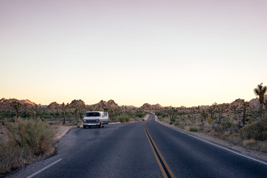 Van parked on the side of a Californian desert highway with it's door open.