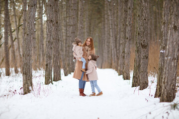 mother with little daughters in a snowy winter forest. travel and recreation with children in winter. family walks in the fresh air during the new year holidays.