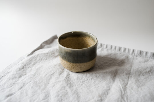 Handmade two toned neutral and light blue modern ceramic pottery cup on white table