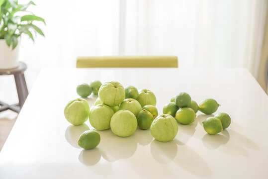 Fresh guava and lemon fruit on white kitchen table.
