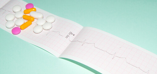 Medications in the form of tablets for oral administration against the background of an electrocardiogram. The heartbeat is shown on the graph, blue background