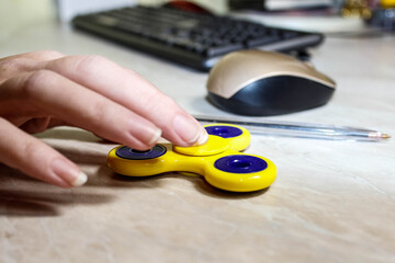 The hand that spins the fidget spinner on the computer table.