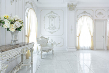 luxury royal posh interior in baroque style. very bright, light and white hall with expensive oldstyle furniture. large windows and stucco ornament decorations on the walls