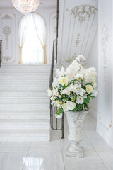 luxury royal posh interior in baroque style. very bright, light and white hall with expensive oldstyle furniture. chic wide marble staircase leading to the second floor
