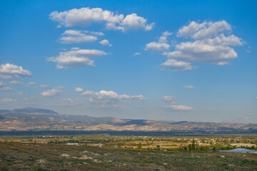 Fototapeta na wymiar Panoramic view onto eastern part of Laodicea, antique city near Denizli, Turkey. It's shown scattered stone pieces of ancient structures. Modern city & mountains are on background