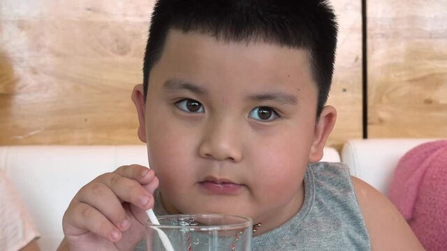 Chubby Asian Child Boy Drinking Water And Spitting Out