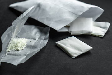 A dose of powdered medicine, packed in individual sachets. Close-up, on a black background....