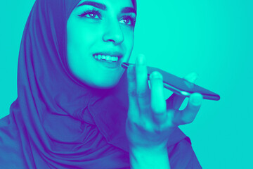 Recording voice. Close up portrait of muslim woman isolated on studio background. Modern and trendy...
