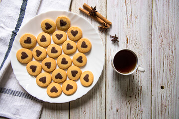 Top view of chocolate chip heart shaped cookies and cinnamon sticks and cup of coffee with use of selective focus.