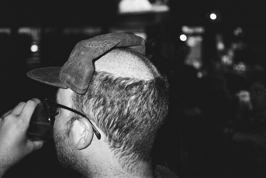 young male with shaved head drinking beer