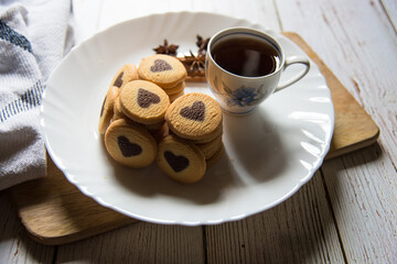 Close up of cup of coffee with cookies in a white plate with use of selective focus.