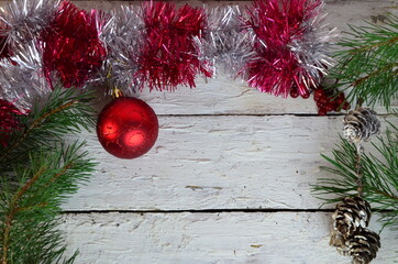 Christmas frame of spruce, red ball branch of a christmas tree, a gift tied with a red ribbon on a white wooden background christmas decorations. Copy space. New Year lights. Flat lay