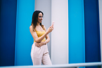 Cheerful woman with earphones using smartphone