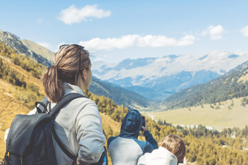 Fototapeta premium A group of tourists gaze at the impressive mountain landscape and take photos on a sunny autumn day. Russia, Arkhyz