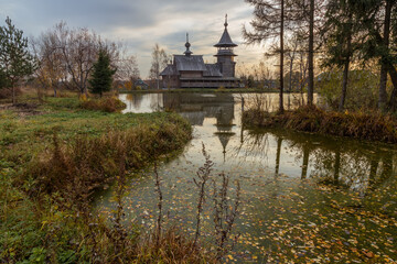 Fototapeta premium Wooden orthodox church of the Annunciation and its reflection in the lake on an autumn day. Moscow region, Sergiev Posad district. The Blagoveshheniye village
