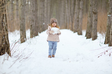 little girl play in the winter forest and make snow balls for the snowman. walking in any weather. new year vacations. happy childhood.