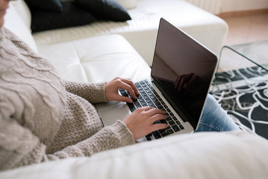 Side view of a woman using a laptop on a sofa