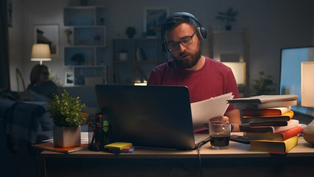 Man holding an online meeting at home in his living room late at night