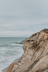 Vertical shot of cliffs surrounded by the sea under a cloudy sky - great for wallpapers