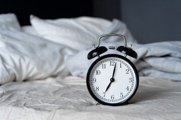 Stylish alarm clock with a bell. The hands show 7 hours. Wake up time