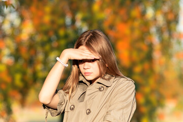 A young girl poses against the background of an autumn garden