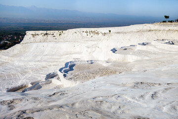 Natural travertine pools or terraces in Pamukkale, Turkey. White color of rocks caused by carbonate minerals. Nature reserve included in UNESCO & attracting tourists from all the world