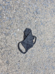 Fototapeta premium A mask made of black stretch fabric improperly thrown away on public roads. This can cause problems in the COVID-19 epidemic, the correct disposal is to put in a sealed plastic bag and dispose in bin 