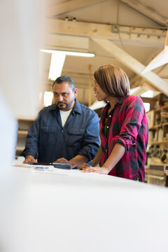 Two multi ethnic workers talking at a work table in a small cabi
